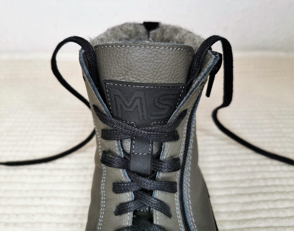 egy bal lábra való, szürke Magical Alaskan X barefoot bokacsizma bokarésze közelről, elölnézetben